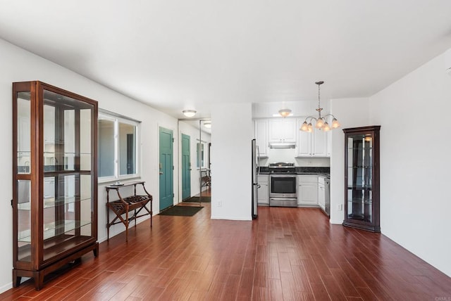 kitchen with pendant lighting, white cabinets, appliances with stainless steel finishes, and dark wood-type flooring