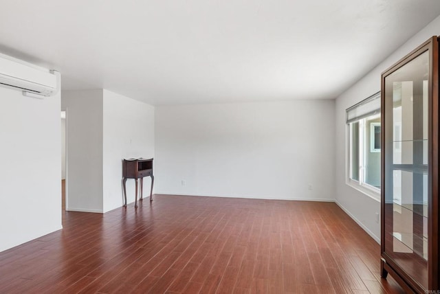 spare room featuring a wall mounted air conditioner and dark wood-type flooring