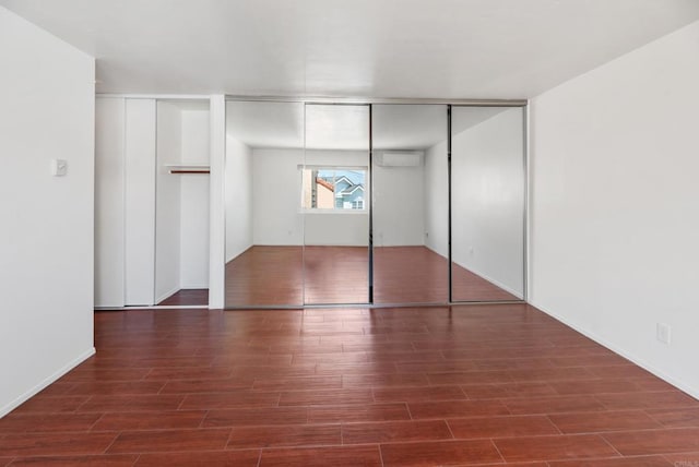 unfurnished bedroom with dark hardwood / wood-style flooring and a wall mounted AC