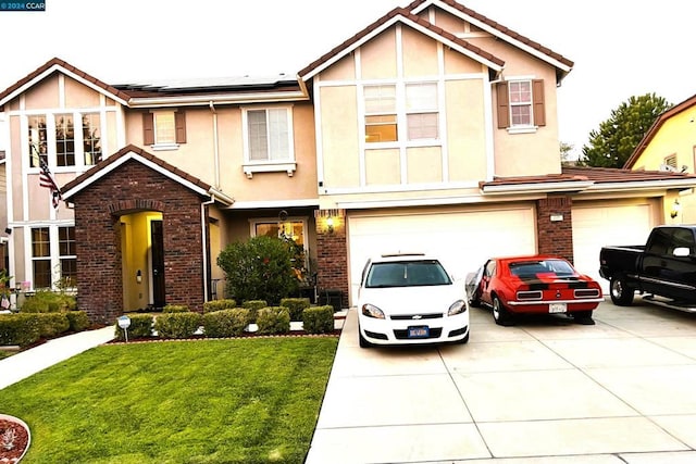 tudor-style house featuring a front yard, solar panels, and a garage