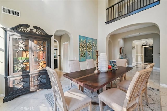 dining space featuring light tile patterned flooring and a high ceiling