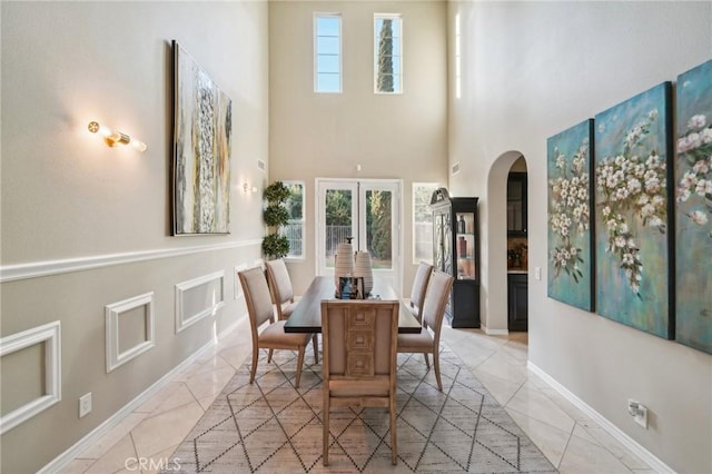 dining area with a high ceiling, french doors, and a healthy amount of sunlight