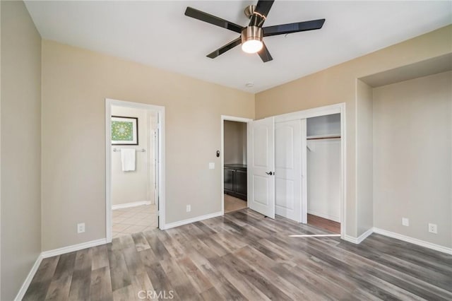 unfurnished bedroom featuring ceiling fan, connected bathroom, wood-type flooring, and a closet