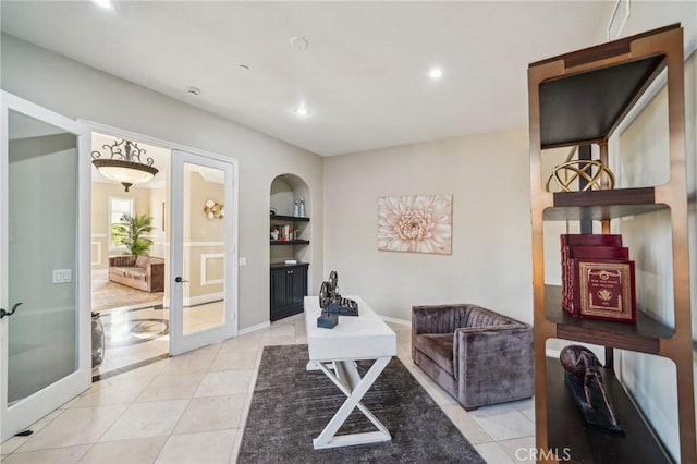 living area with french doors, built in features, and light tile patterned flooring