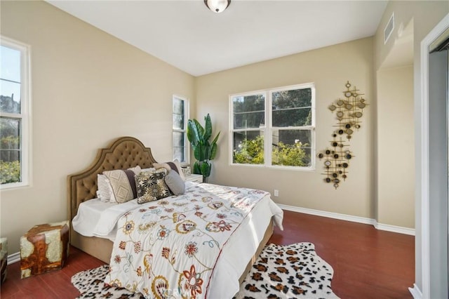 bedroom featuring multiple windows and dark hardwood / wood-style flooring