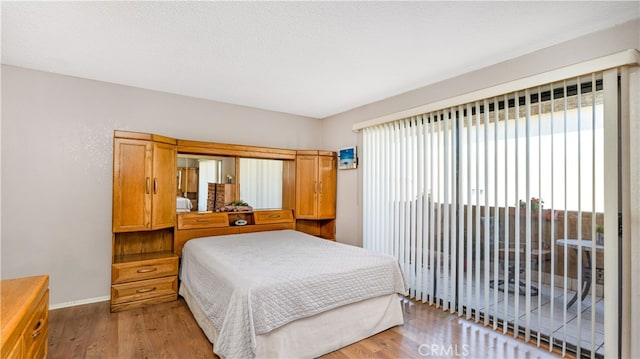 bedroom featuring access to exterior, a textured ceiling, and hardwood / wood-style floors