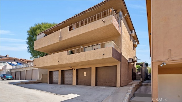 view of building exterior with a garage and a wall mounted air conditioner