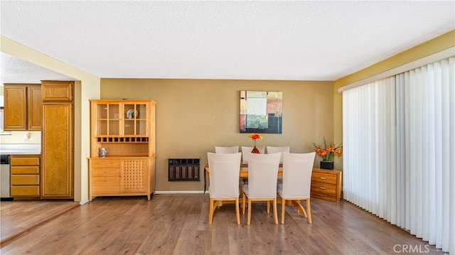 dining space featuring hardwood / wood-style flooring, heating unit, and a textured ceiling