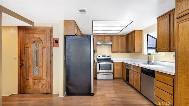 kitchen with stainless steel appliances, light wood-type flooring, and sink