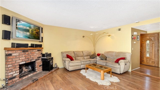 living room featuring a brick fireplace, hardwood / wood-style flooring, and a textured ceiling