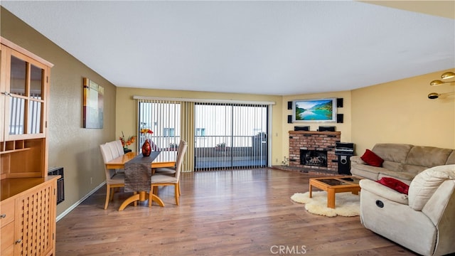 living room with heating unit, a brick fireplace, and hardwood / wood-style floors