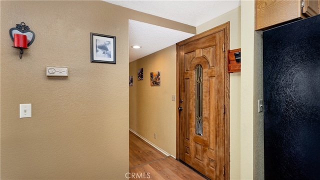 hall with a textured ceiling and light hardwood / wood-style flooring