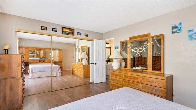 bedroom featuring a closet, dark hardwood / wood-style floors, and a textured ceiling