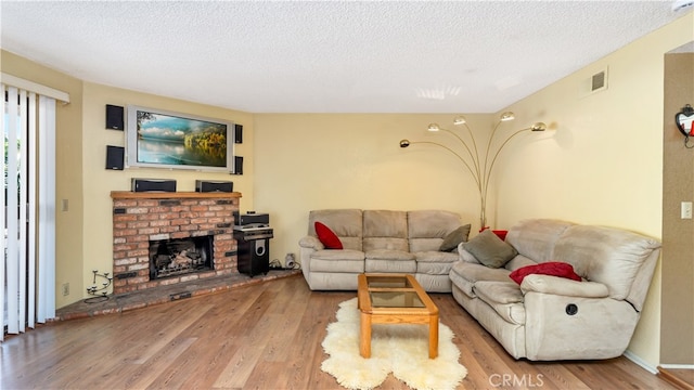 living room featuring light hardwood / wood-style flooring, a textured ceiling, and a fireplace