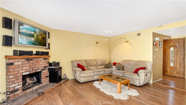 living room with wood-type flooring, a textured ceiling, and a fireplace