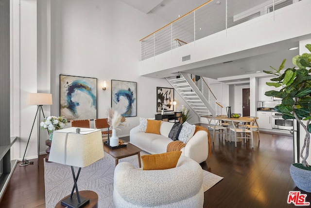 living room with a high ceiling and dark wood-type flooring