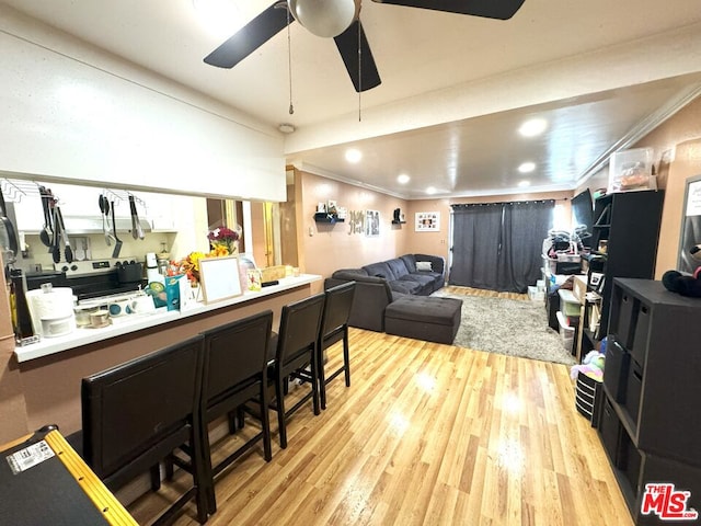 interior space with kitchen peninsula, light hardwood / wood-style floors, ceiling fan, and ornamental molding