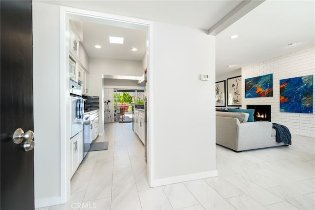 kitchen featuring white cabinetry, stainless steel oven, and a fireplace