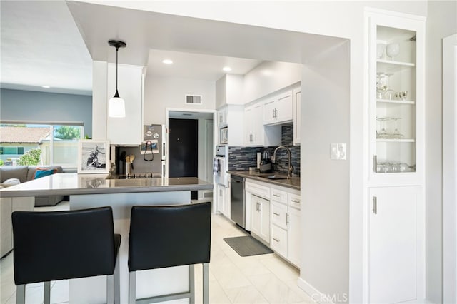 kitchen featuring appliances with stainless steel finishes, decorative backsplash, white cabinets, a kitchen bar, and sink