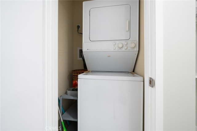 clothes washing area featuring stacked washing maching and dryer