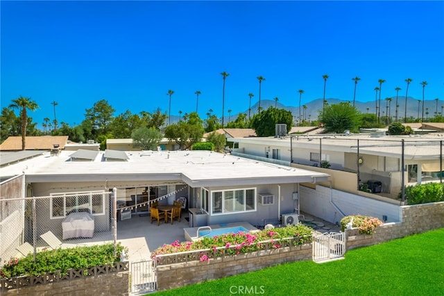 rear view of property featuring a mountain view, a patio area, and a yard