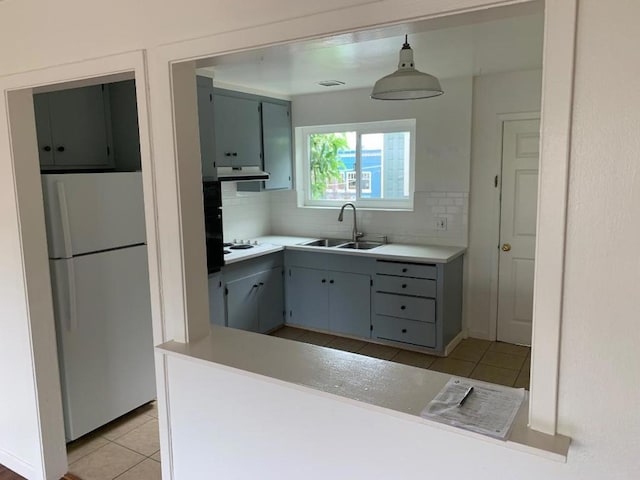 kitchen with hanging light fixtures, decorative backsplash, white appliances, light tile patterned floors, and sink