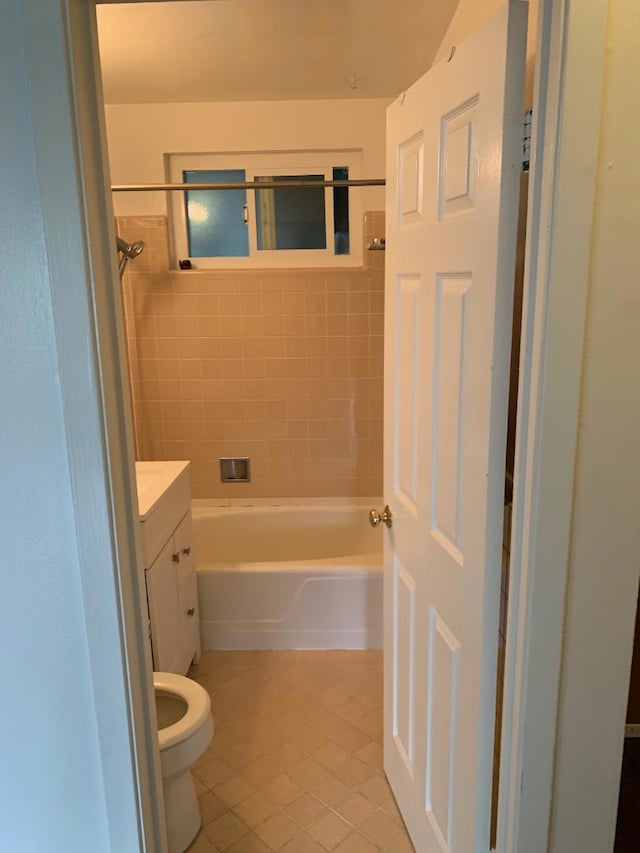 full bathroom featuring tile patterned flooring, tiled shower / bath, vanity, and toilet