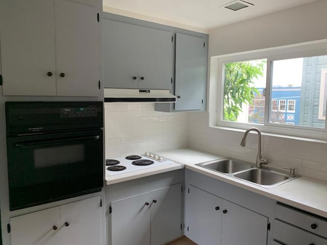 kitchen with decorative backsplash, black oven, white electric cooktop, and sink