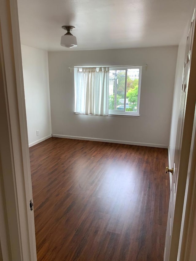 unfurnished room with dark wood-type flooring