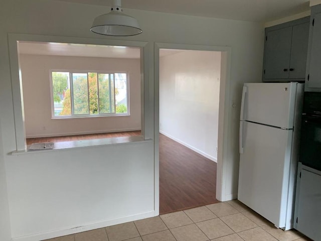 kitchen with light wood-type flooring, oven, and white fridge