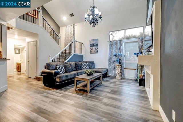 living room featuring hardwood / wood-style flooring, high vaulted ceiling, and a notable chandelier