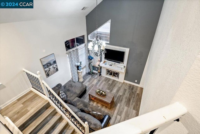 living room featuring wood-type flooring, an inviting chandelier, and high vaulted ceiling