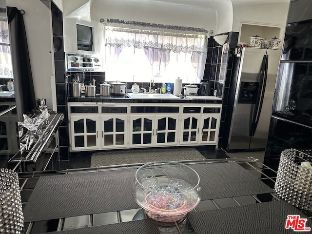 kitchen with dark tile patterned flooring, tile countertops, sink, and stainless steel fridge