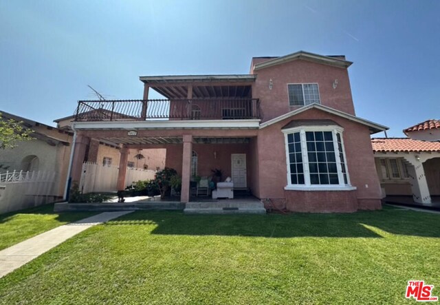 back of property featuring a patio, a balcony, and a yard