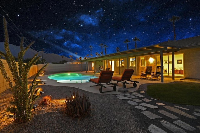 pool at night featuring a patio area