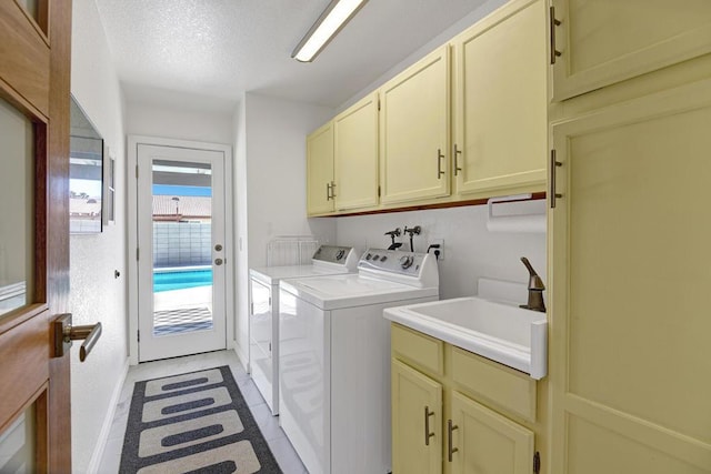 washroom featuring washing machine and clothes dryer, sink, cabinets, a textured ceiling, and light tile patterned floors