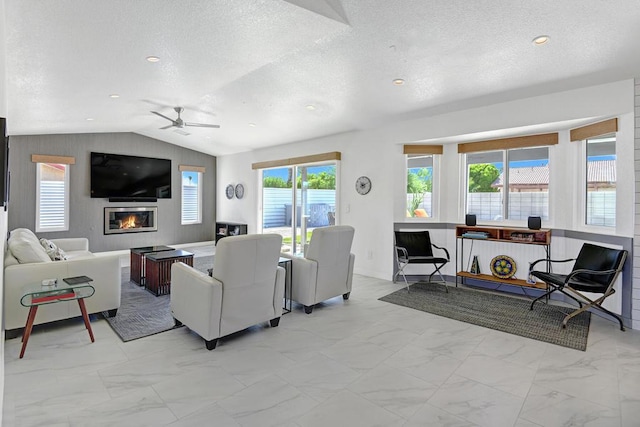 living room with a textured ceiling, ceiling fan, and lofted ceiling