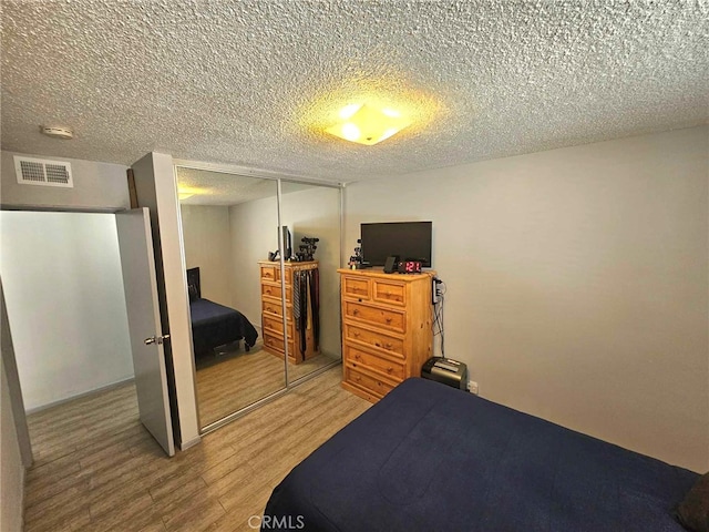 bedroom with hardwood / wood-style floors, a textured ceiling, and a closet