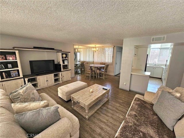 living room featuring a notable chandelier, dark hardwood / wood-style flooring, and a textured ceiling