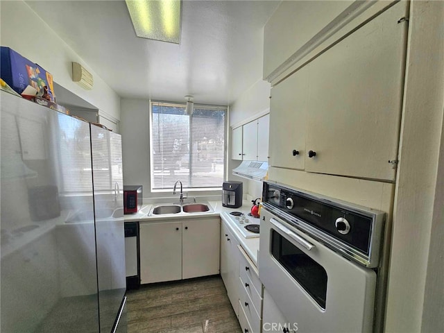 kitchen with white cabinetry, sink, stainless steel appliances, dark hardwood / wood-style flooring, and ventilation hood