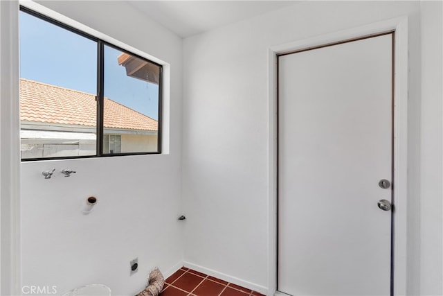 laundry area with hookup for an electric dryer and dark tile patterned flooring