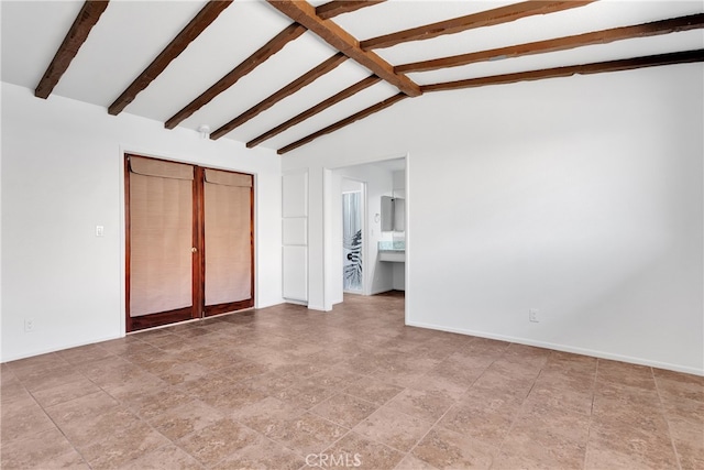 unfurnished bedroom with lofted ceiling with beams and connected bathroom