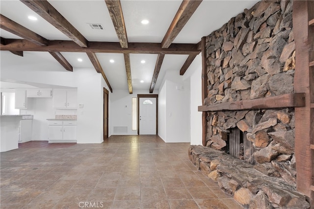 unfurnished living room with beam ceiling and a fireplace