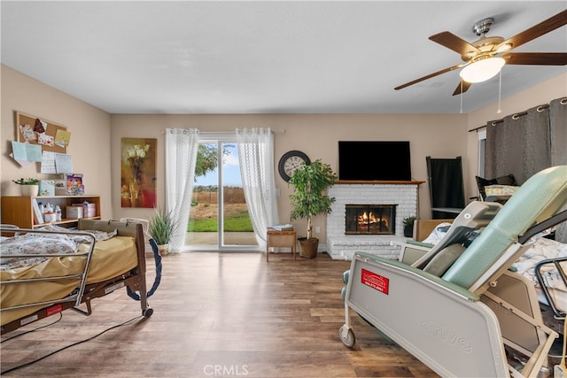 living room featuring a brick fireplace, ceiling fan, and hardwood / wood-style flooring