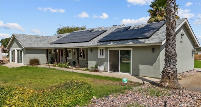 back of property featuring a yard and solar panels