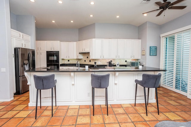 kitchen with white cabinets, an island with sink, sink, stainless steel fridge with ice dispenser, and a breakfast bar area