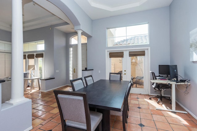 tiled dining space with a healthy amount of sunlight, a towering ceiling, french doors, and ornate columns