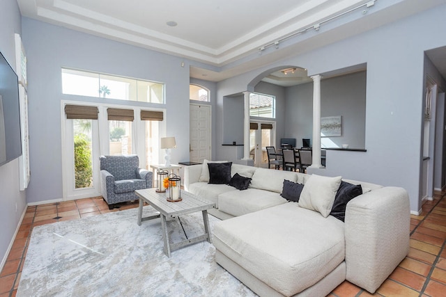 tiled living room with a tray ceiling, decorative columns, plenty of natural light, and rail lighting