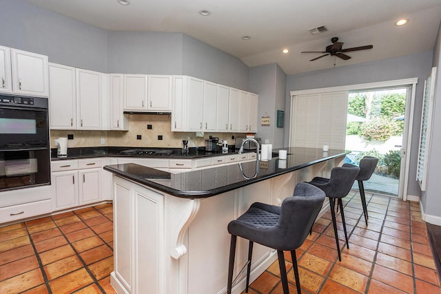 kitchen with black appliances, a center island with sink, and a kitchen bar