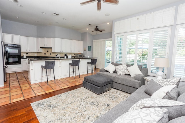 living room with ceiling fan, light wood-type flooring, and sink